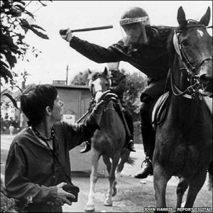Офицер конной полиции замахнулся для удара  дубинкой по голове Лесли Болтон - женщины с фотоаппаратом в руках, которая выступала против закрытия шахт. (http://news.bbc.co.uk/local/sheffield/hi/people_and_places/history/newsid_8217000/8217946.stm)